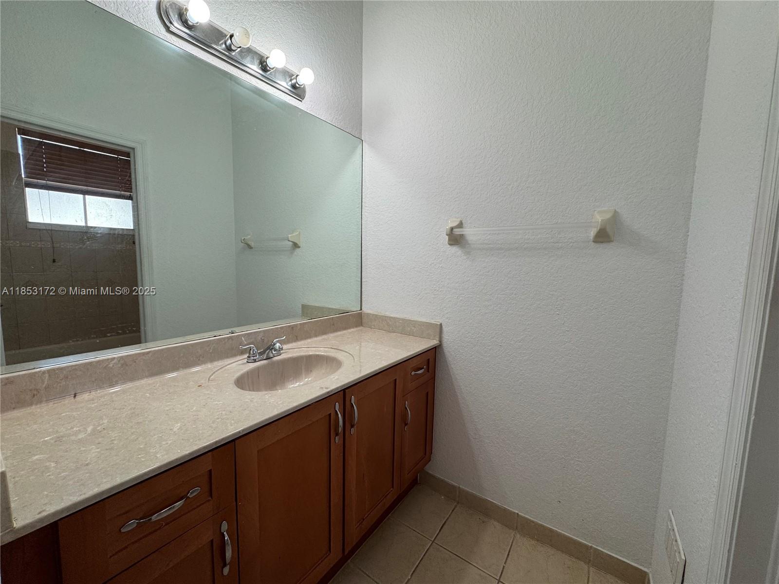 14046 Southwest 49th Street, Unit 16 Miramar, FL 33027 - Photo 11 of 22 a bathroom with a granite countertop sink and a mirror