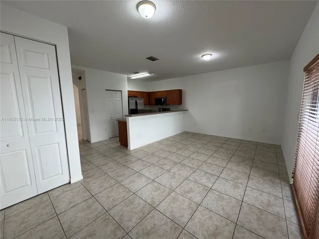 an empty room & kitchen space with a sink
