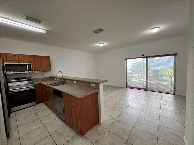 a large kitchen with kitchen island granite countertop a stove a sink and a refrigerator