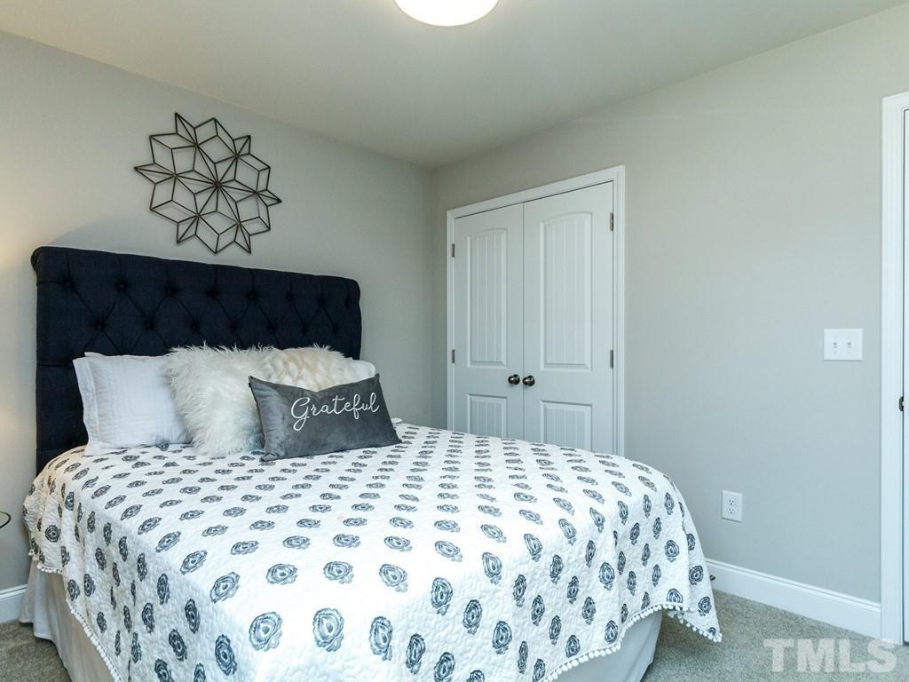 204 Kentigern Drive, Unit 34 Raleigh, NC 27606 - Photo 6 of 33 a large bed sitting in a bedroom and a lamp
