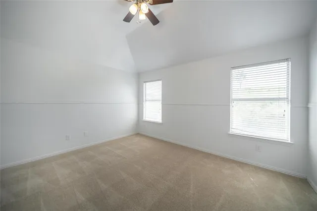 an empty room with a chandelier fan and windows