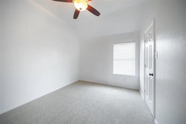 an empty room with a chandelier fan and windows
