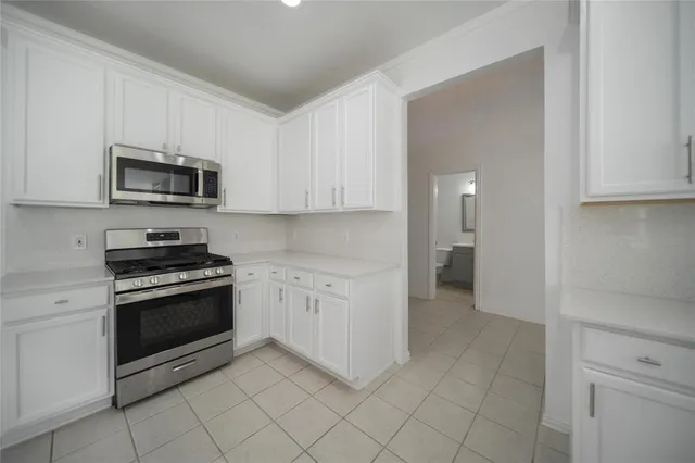a kitchen with granite countertop white cabinets and stainless steel appliances