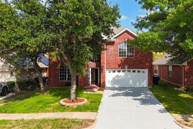 a front view of a house with a garden and tree