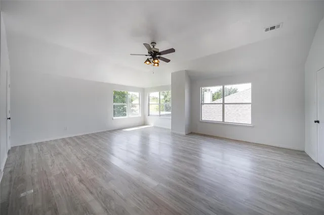 an empty room with wooden floor and windows