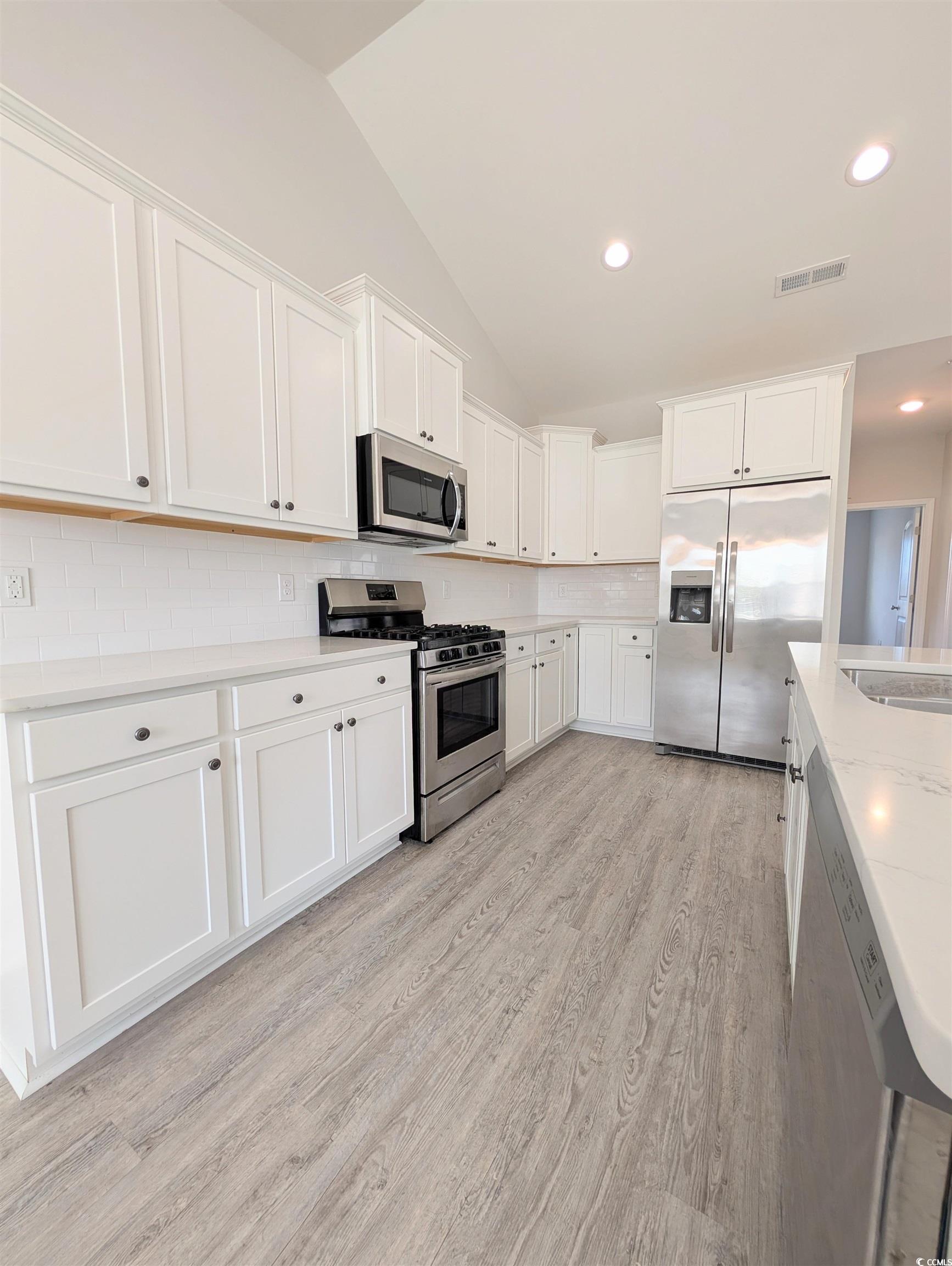 351 Lakota Loop Longs, SC 29568 - Photo 6 of 31 Kitchen with stainless steel appliances, decorative backsplash, white cabinets, light wood-style flooring, and lofted ceiling