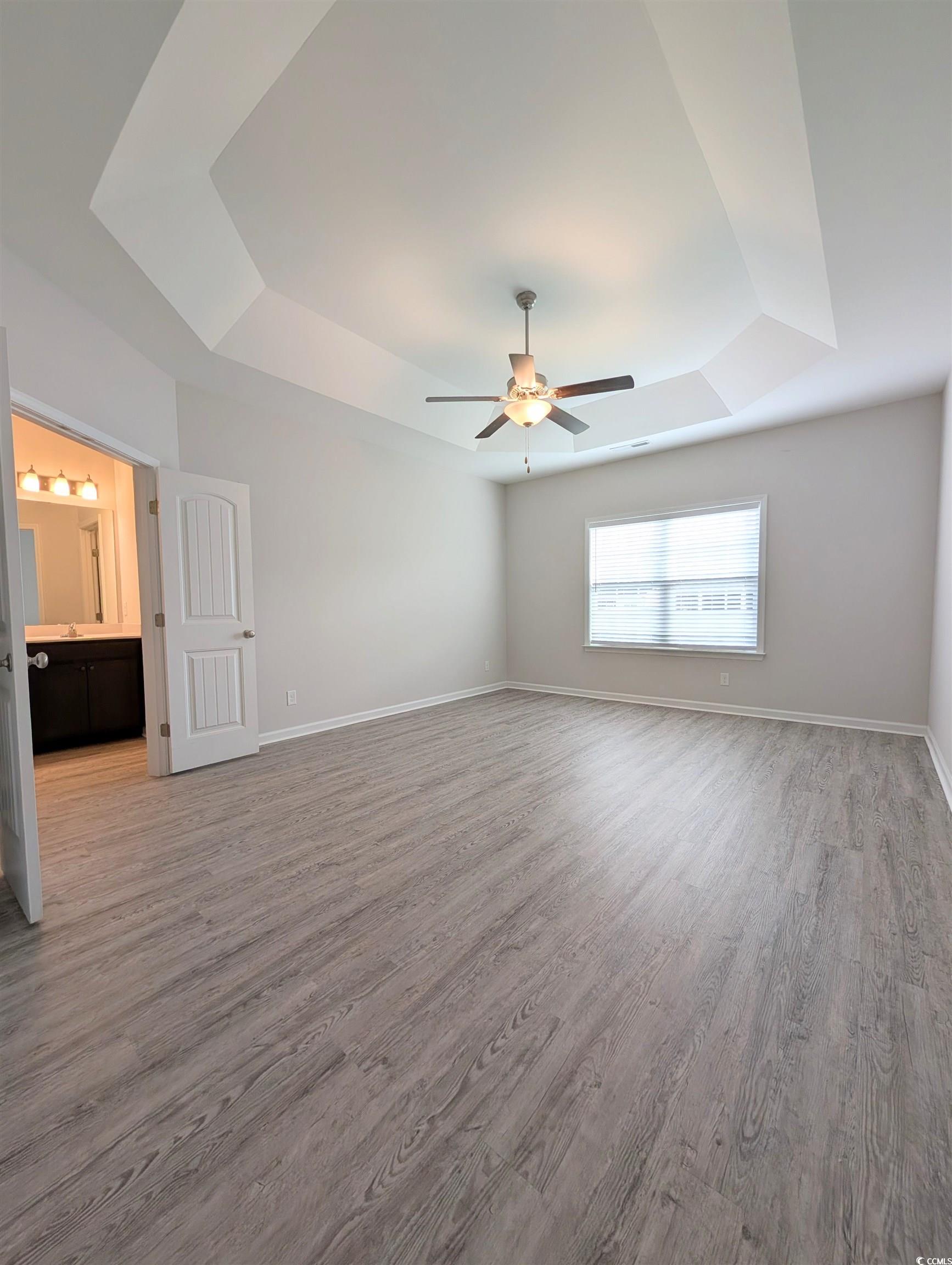 351 Lakota Loop Longs, SC 29568 - Photo 8 of 31 Unfurnished bedroom with a raised ceiling, light wood-style flooring, a ceiling fan, and connected bathroom