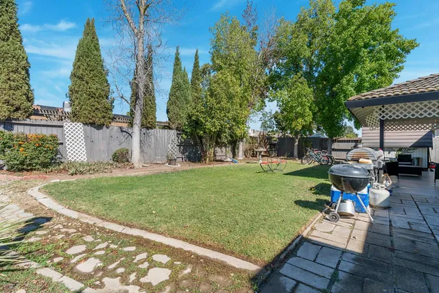 a view of backyard with table and chairs and a large tree