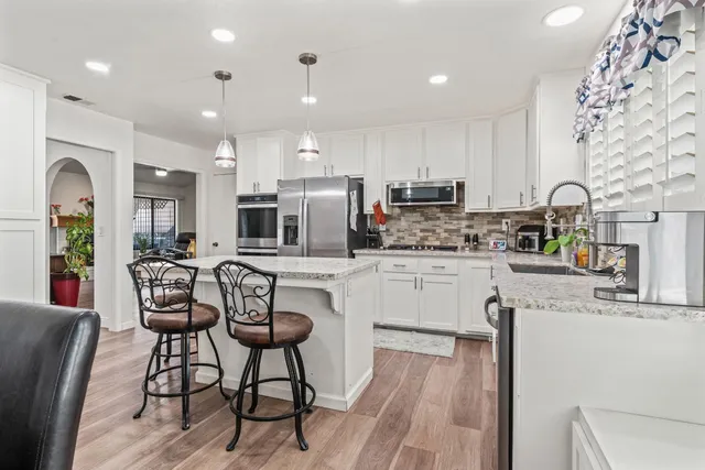 a kitchen with stainless steel appliances kitchen island granite countertop a refrigerator and microwave