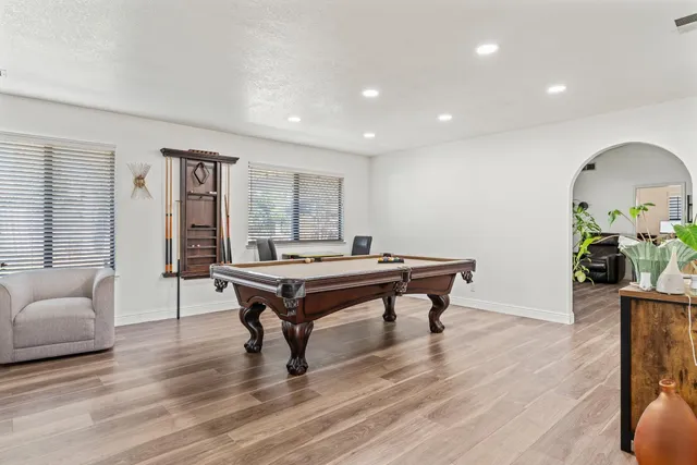a room with furniture pool table wooden floor and windows