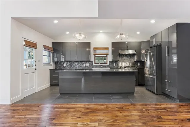 a kitchen with kitchen island a counter top space a sink stainless steel appliances and cabinets
