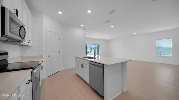 a view of kitchen with kitchen island wooden cabinets and refrigerator