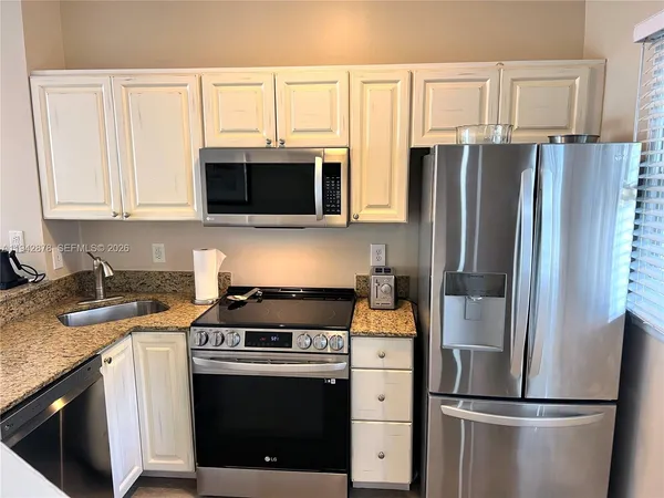 a kitchen with stainless steel appliances granite countertop a stove a microwave and a refrigerator