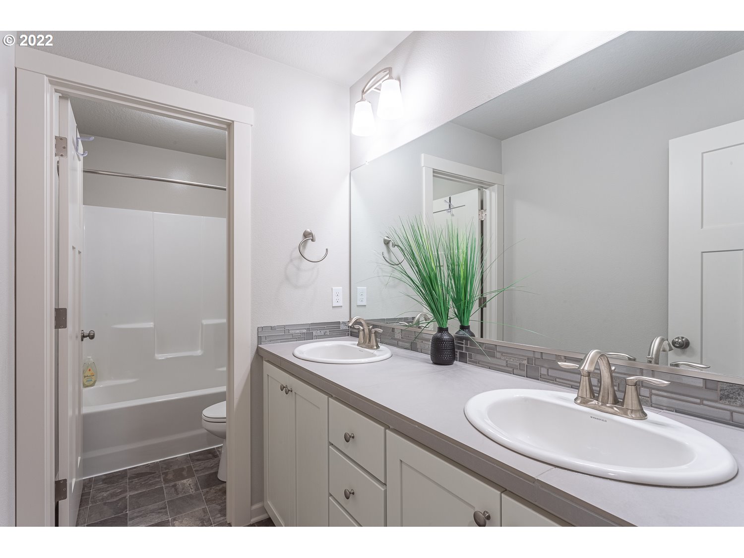 3821 South 41st Place Ridgefield, WA 98642 - Photo 28 of 32 a bathroom with a granite countertop sink a mirror a vanity and a bathtub