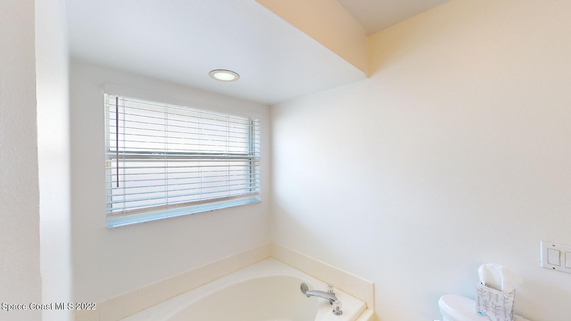 6801 Cecil Road Cocoa, FL 32927 - Photo 45 of 66 a bathroom with a bathtub a toilet and a window