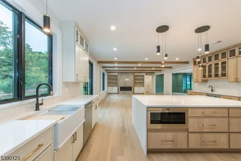 a large white kitchen with kitchen island a stove a sink and a large window