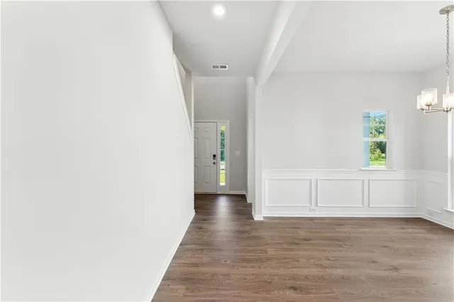 a view of an empty room with window and wooden floor