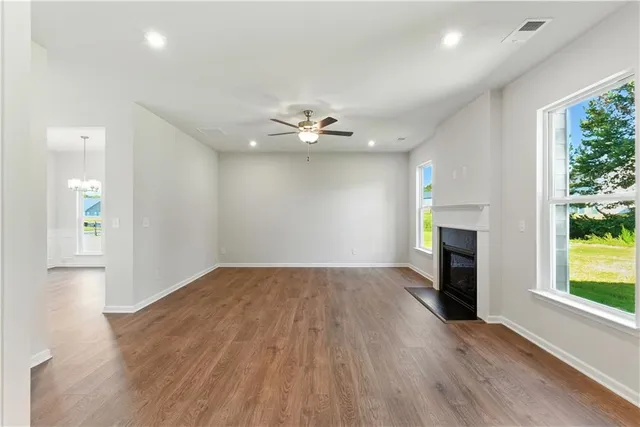 a view of an empty room with kitchen appliances and a ceiling fan