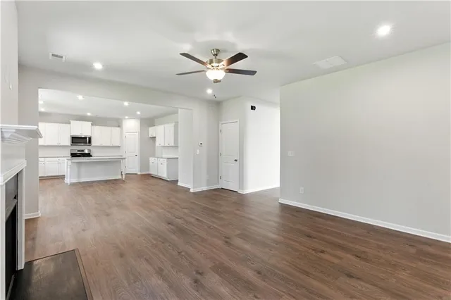 a view of a livingroom with a fireplace a ceiling fan and wooden floor