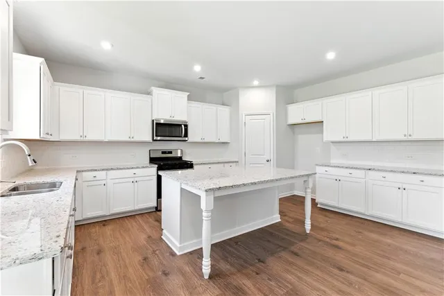 a kitchen with stainless steel appliances granite countertop a stove a sink and a microwave