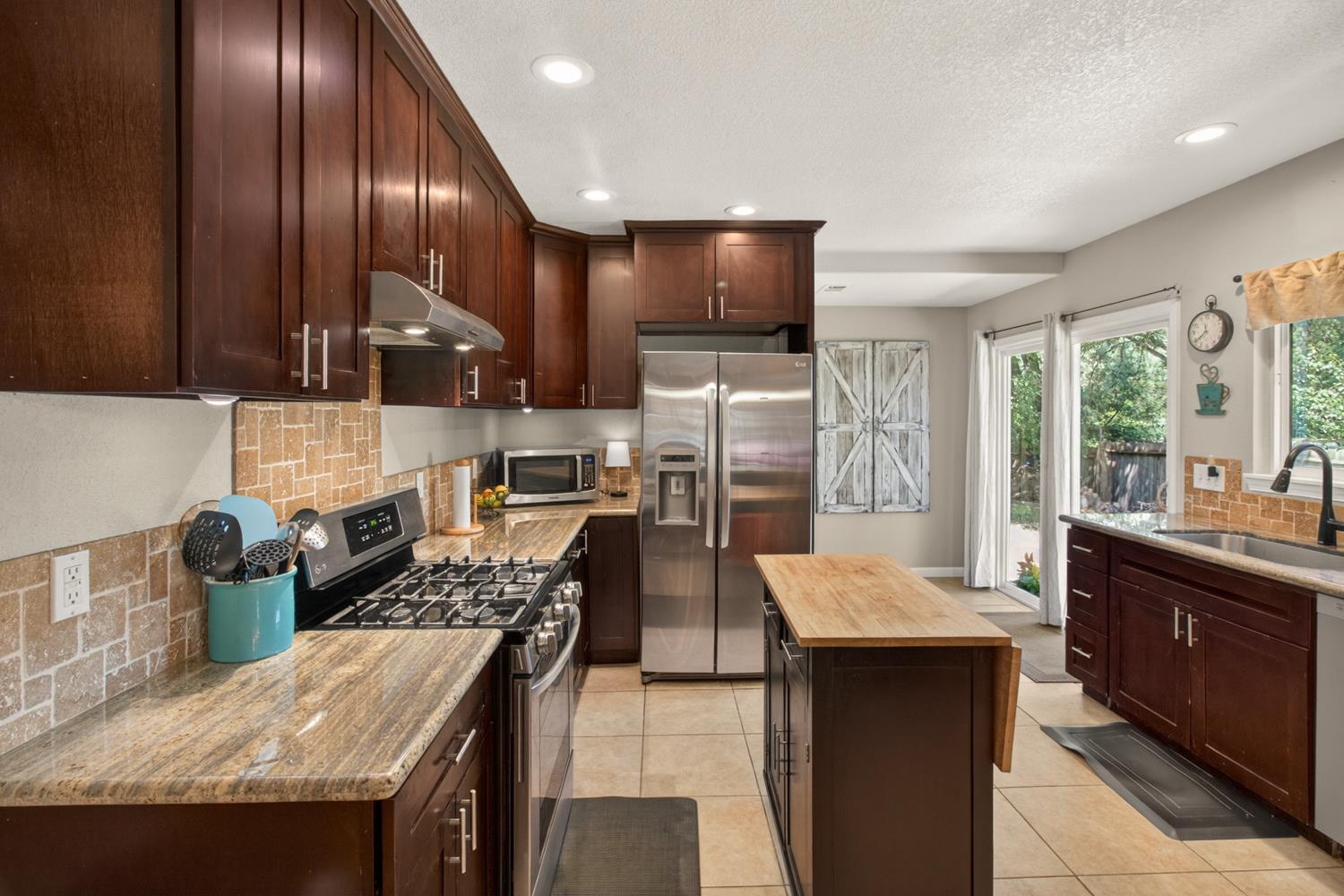 6332 Horseshoe Bar Road Loomis, CA 95650 - Photo 6 of 85 Kitchen featuring granite countertops, dark wood cabinetry, stainless steel appliances, tile flooring, and direct outdoor access via double glass doors