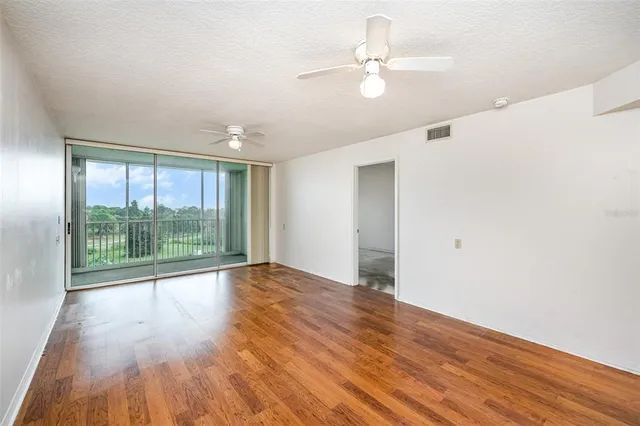 a view of an empty room with wooden floor and a window