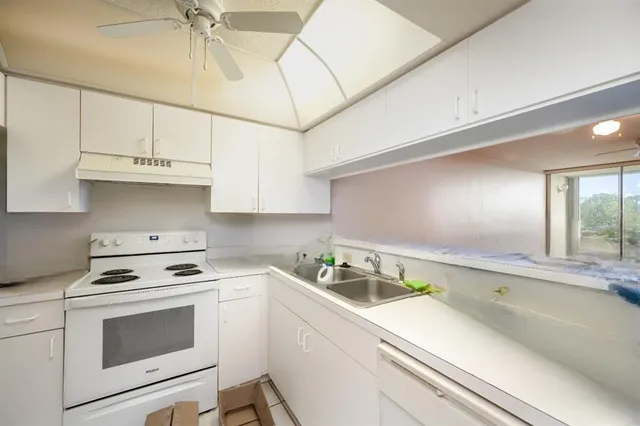 a kitchen with granite countertop a sink cabinets and stainless steel appliances