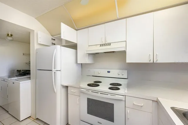a white refrigerator freezer and a stove sitting inside of a kitchen