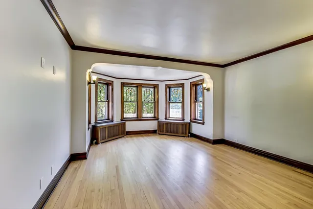 a view of an empty room with glass door and wooden floor