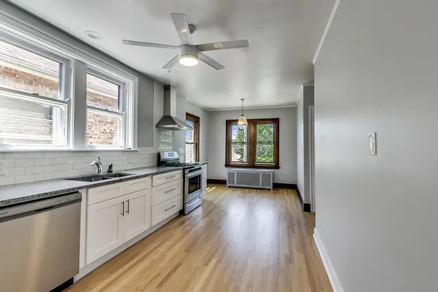 a kitchen with granite countertop a sink a counter space appliances and windows