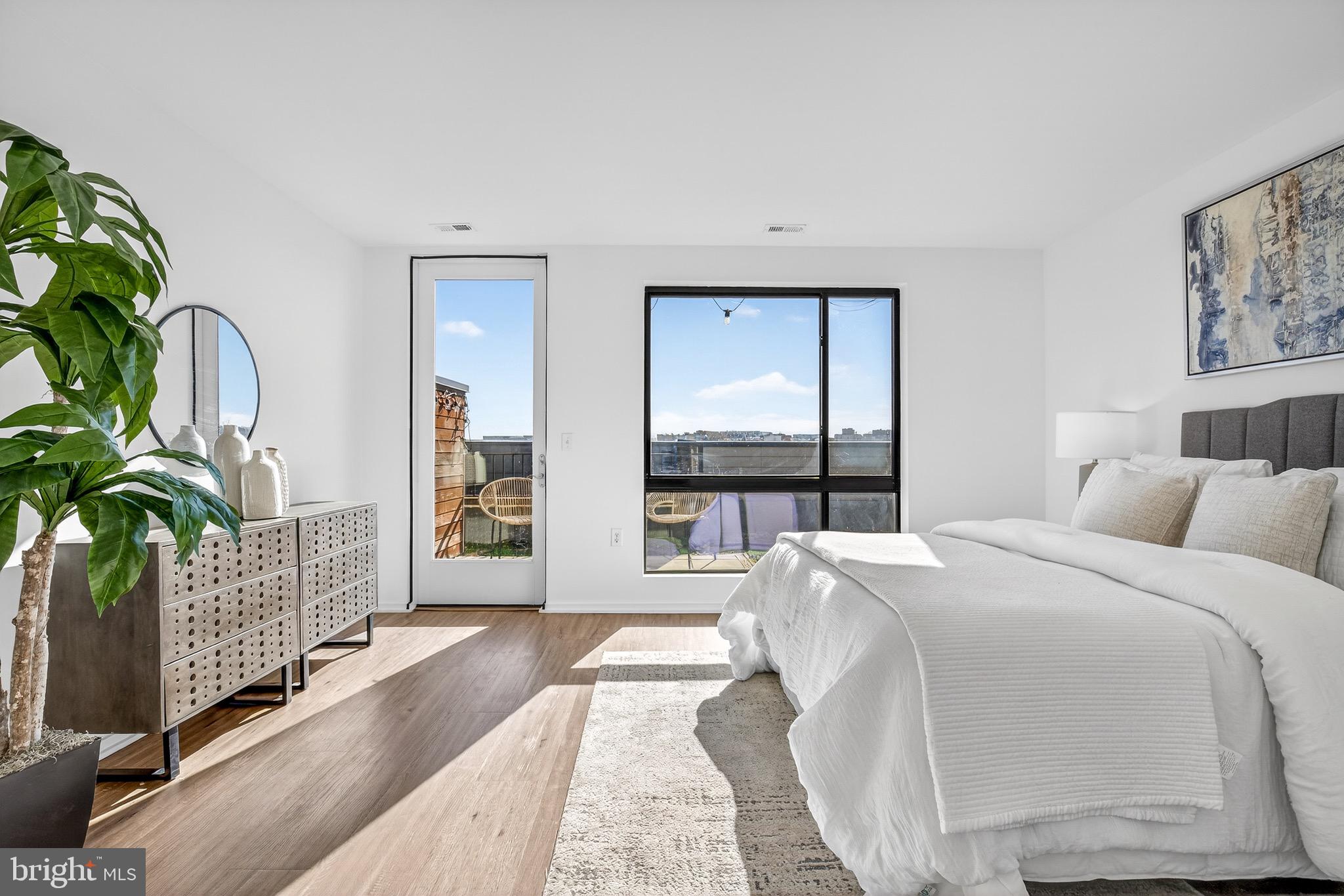 1550 11th Street Northwest, Unit 407 Washington, DC 20005 - Photo 15 of 20 a spacious bedroom with a balcony a large bed and a potted plant