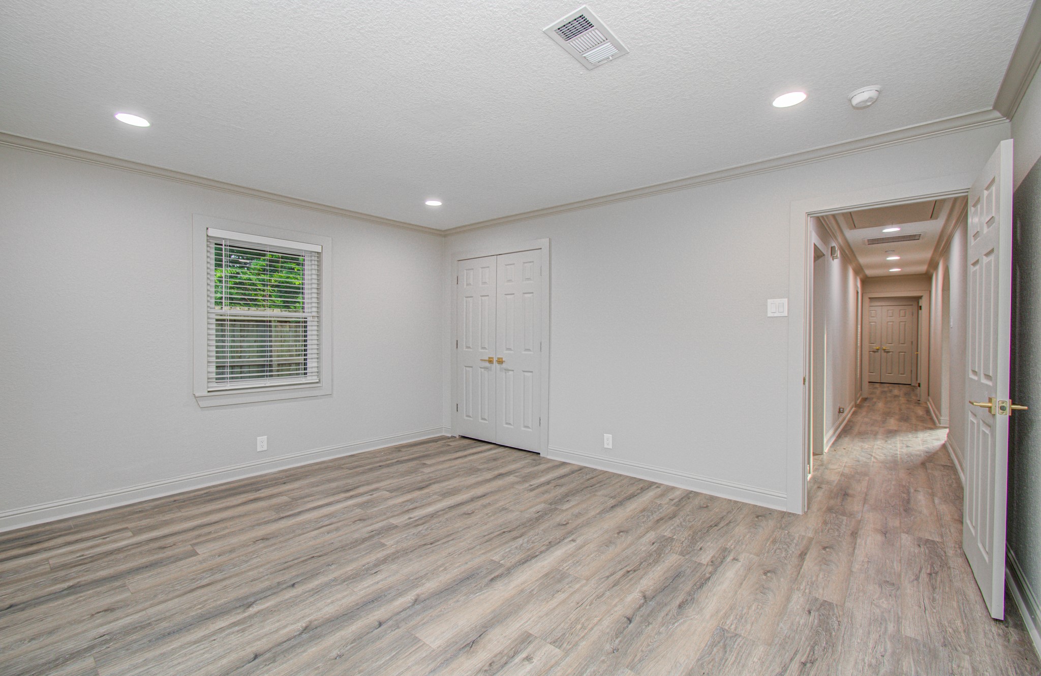 1801 Benbow Way Houston, TX 77080 - Photo 28 of 32 Bright room with light wood flooring, neutral walls, and recessed lighting. Features a window with blinds, a double-door closet, and access to a hallway.