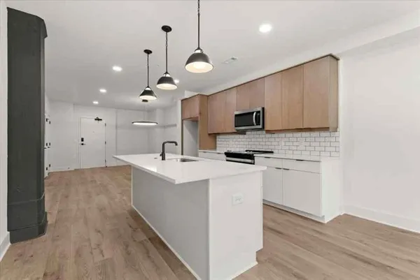a large kitchen with kitchen island a stove a sink a center island and wooden floor