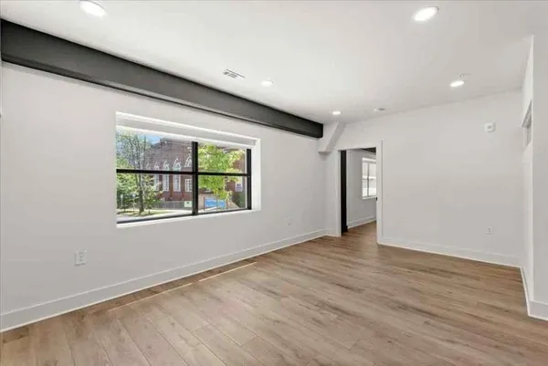 a view of an empty room with wooden floor and a window