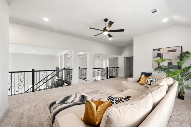 a living room with hard wood flooring furniture and a ceiling fan