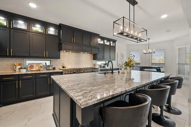 a kitchen with stainless steel appliances granite countertop a sink a counter and chairs