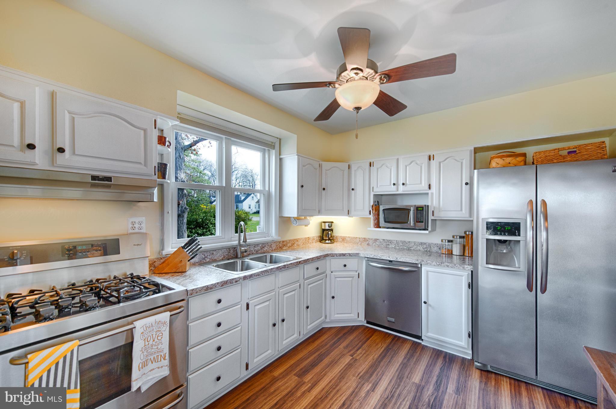 8110 Hillendale Road Baltimore, MD 21234 - Photo 16 of 30 a kitchen with stainless steel appliances a stove a sink dishwasher a refrigerator and white cabinets with wooden floor