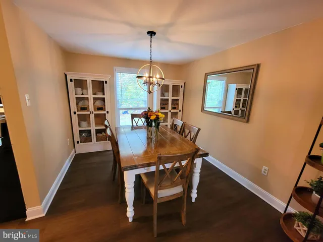 a dining room with wooden floor a chandelier a glass table and chairs