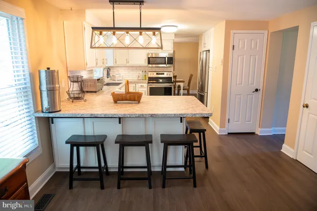 a kitchen with a sink dishwasher stove and white cabinets with wooden floor