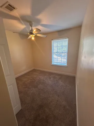 a view of an empty room with a chandelier fan