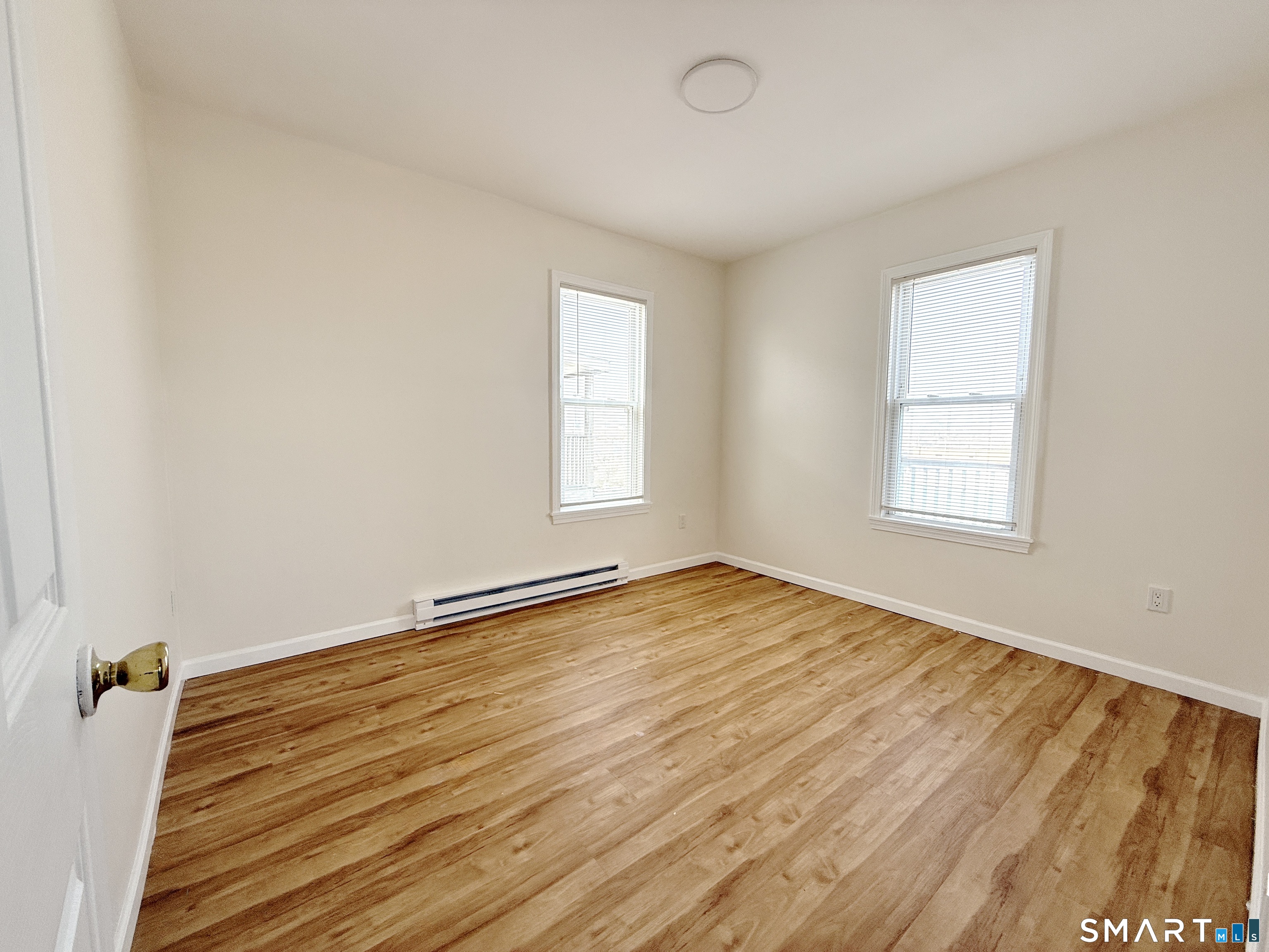 70 Lindley Street Bridgeport, CT 06604 - Photo 5 of 8 an empty room with wooden floor and windows