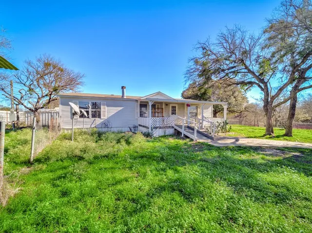 a view of a house with a big yard and large trees