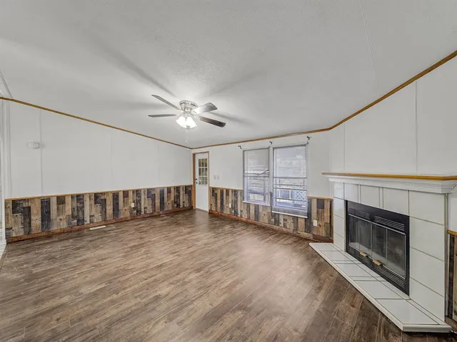 a view of an empty room with wooden floor fireplace and a window
