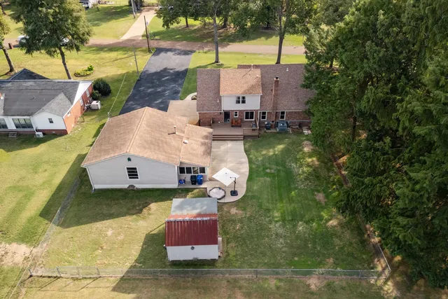 an aerial view of residential house with outdoor space and trees all around