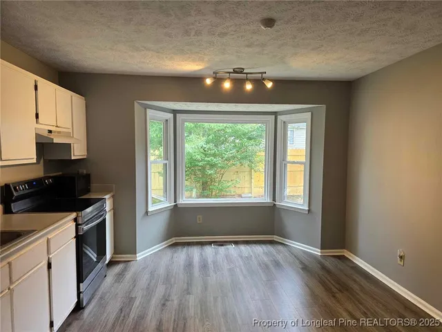 a kitchen with granite countertop wooden floors stainless steel appliances and sink