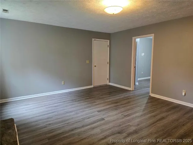a view of an empty room with wooden floor and closet