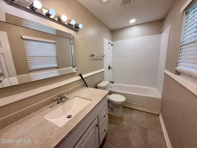 a bathroom with a granite countertop sink a toilet a mirror and shower