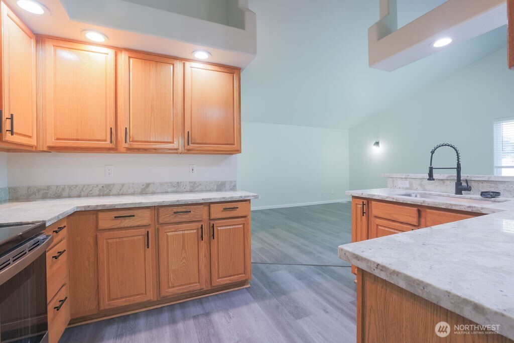 10720 Eustis Hunt Road East Graham, WA 98338 - Photo 12 of 27 a kitchen with stainless steel appliances granite countertop a sink a microwave cabinets and wooden floor