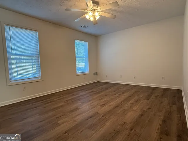 a view of an empty room with window and wooden floor