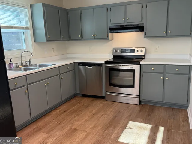 a kitchen with granite countertop a refrigerator and a stove top oven